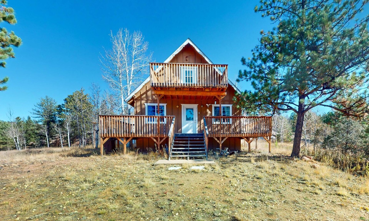 Florissant House | A-frame home lined by trees with wood stove, balcony, children's items, & W/D